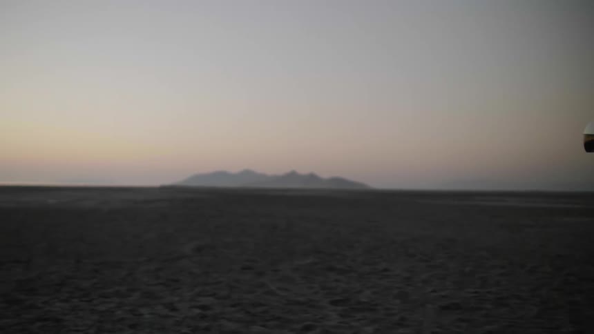A boy in a helmet runs across the sandy beach