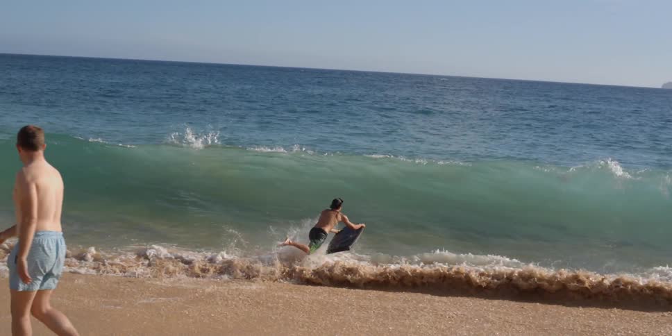 Man runs into the water with a boogie board