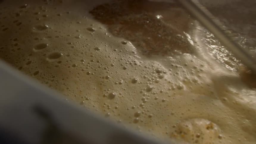 Beer is stirred in a large vat at a brewery