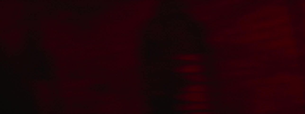 A man is punching a heavy bag in the dark gym