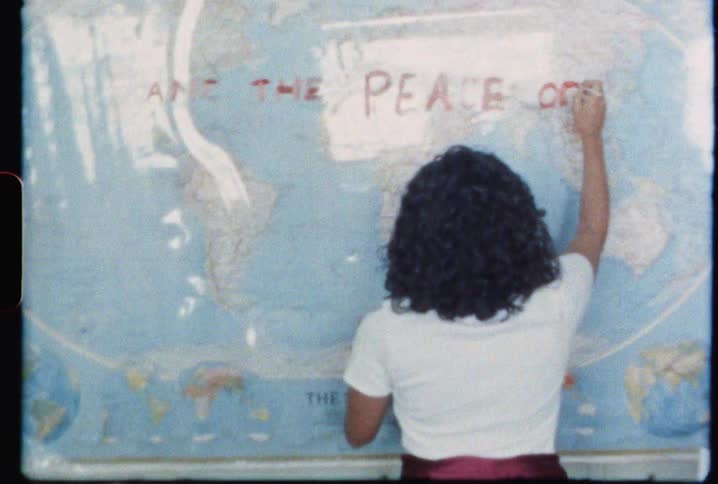 A woman writes a message on a world map on the wall