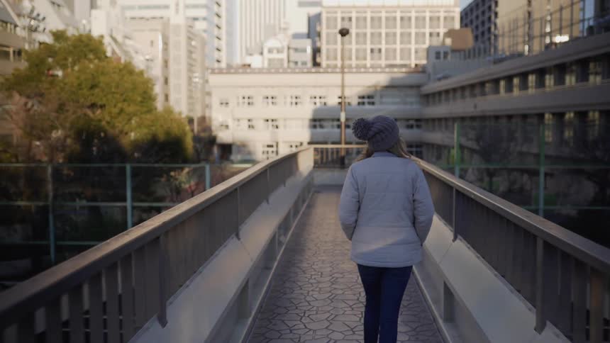 A woman is walking over a platform near buildings