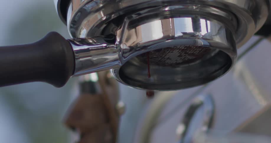 Espresso is dripping from an espresso maker inside in daylight