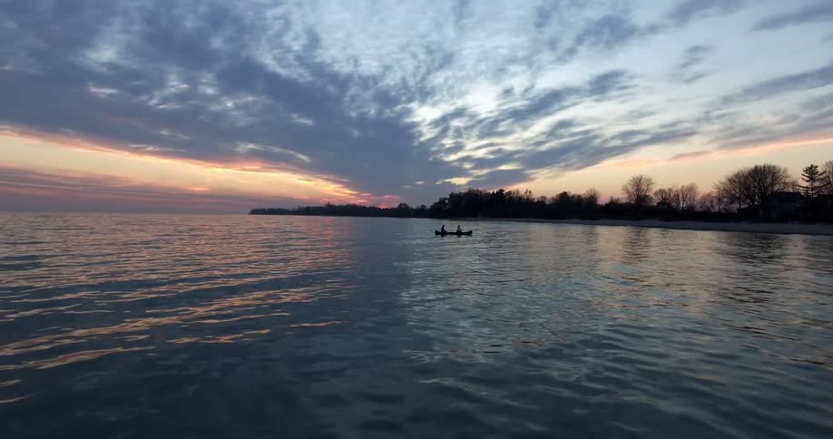 Two people sitting in a boat in water after sunset