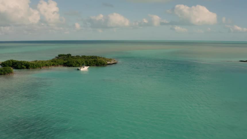 A boat is floating at anchor next to an island in a lagoon in daylight