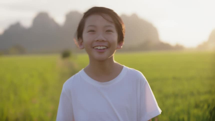 The child is smiling as he walks through the grass