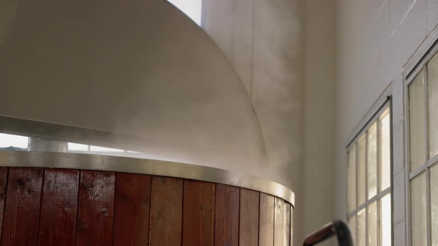 Steam floats up from a wooden barrel