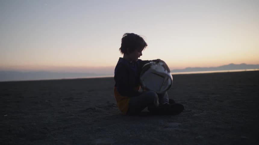 A young boy removes a helmet