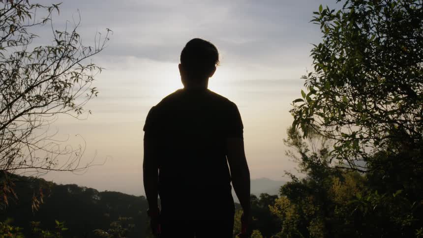 A man stands in the shade on the hill