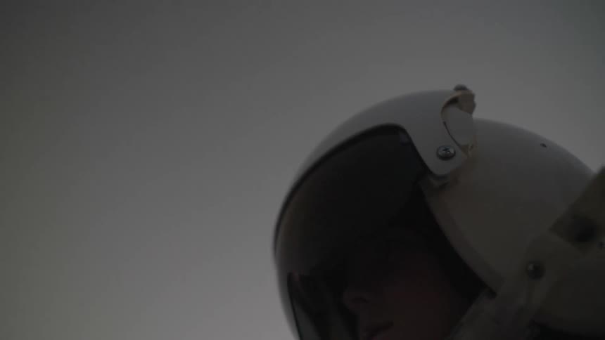 A young boy wears a pilots helmet outside