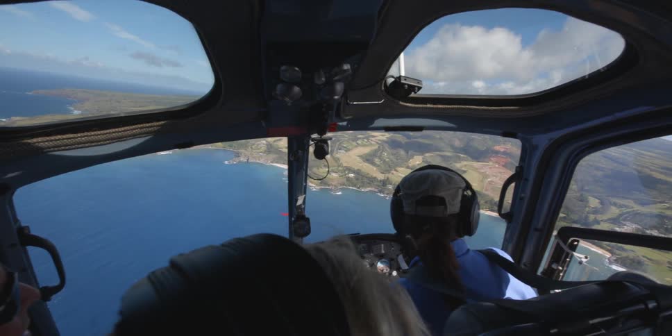 People in a helicopter flying over water and the coastline