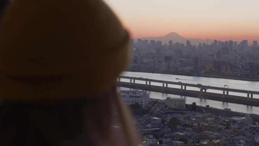 Young woman gazes out of a window at downtown Tokyo