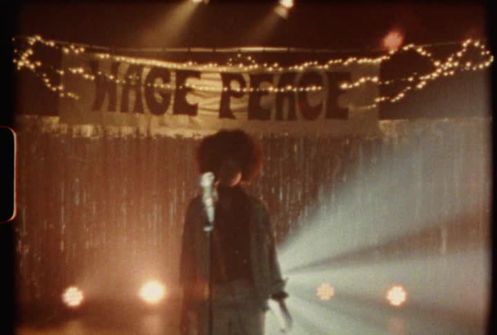 A woman walks on stage as lights shine around