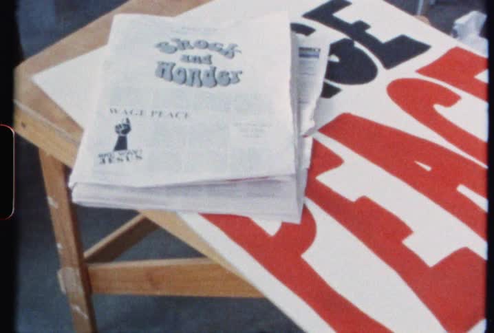 The desk has a newspaper and sign on it