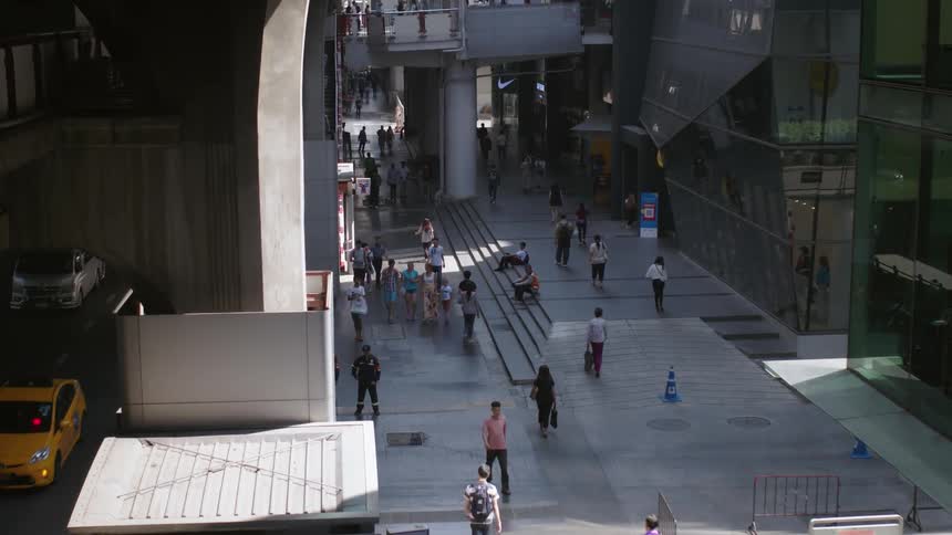 People walk past the tall buildings and road