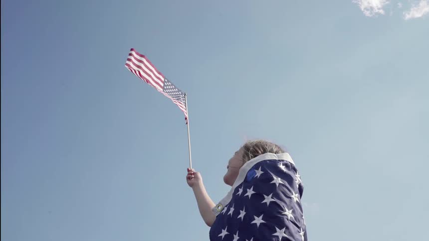 A child is waving a flag in the clear sky