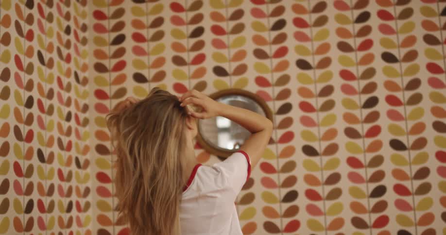 A woman brushes her hair in front of a mirror
