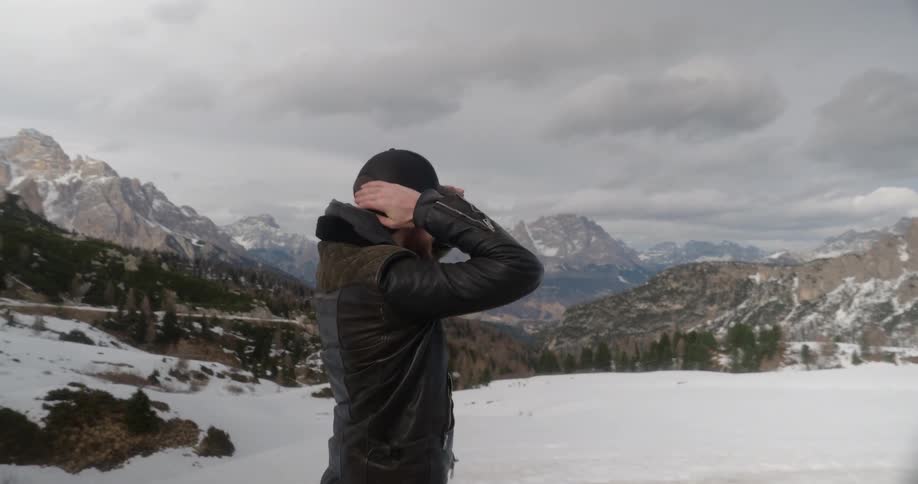 Man putting on his baseball cap in a snowy wilderness