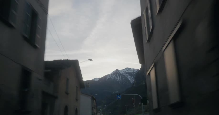 An alleyway opens up into a city with a mountain in the distance