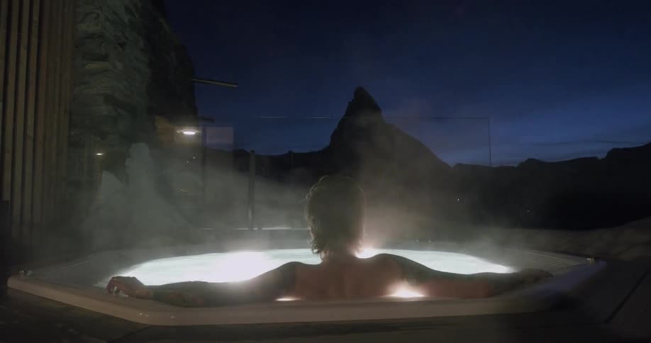 Man relaxing in an outdoor hot tub on a cloudy evening