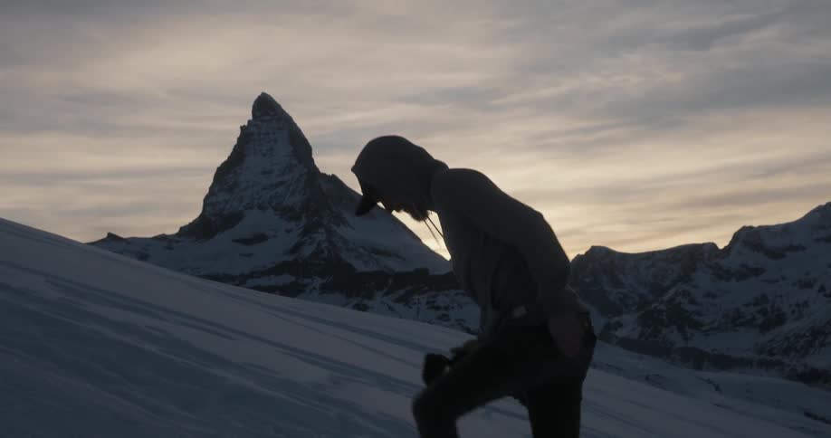 A man is hiking uphill holding a camera