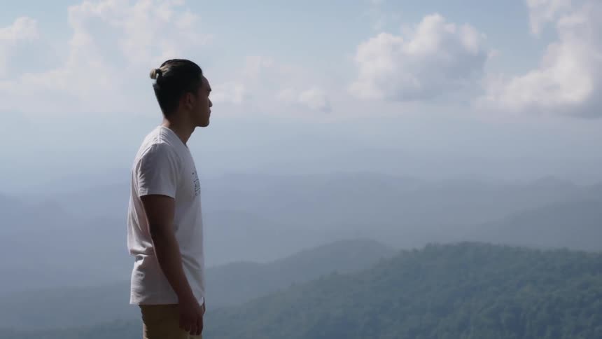 A man stands on the ledge of the mountain