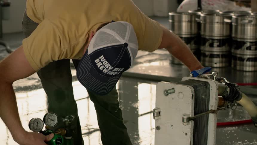 A man is working in a brewery on a machine