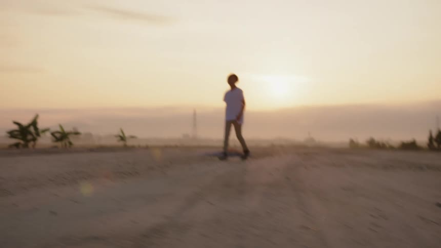 A person walks over the desert at sunset