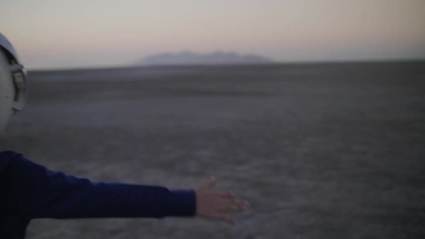 A young boy runs outside with a helmet on in the desert at sunset