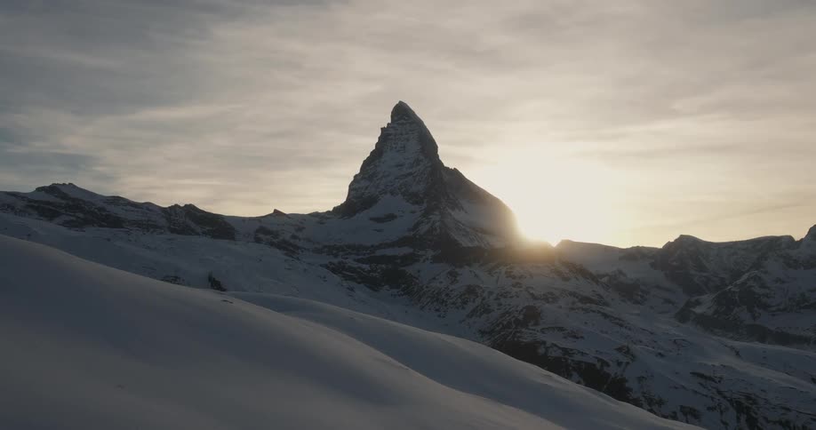 The sun shines over a a snowy mountain
