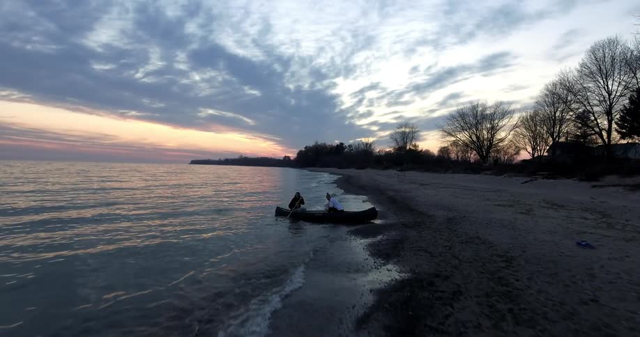 People coming ashore on a canoe at sunset
