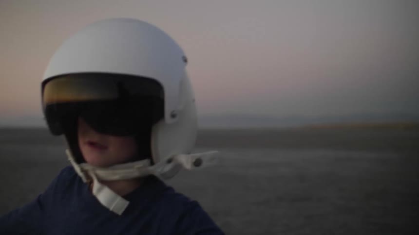 A lonely boy runs across the sandy wilderness in a helmet