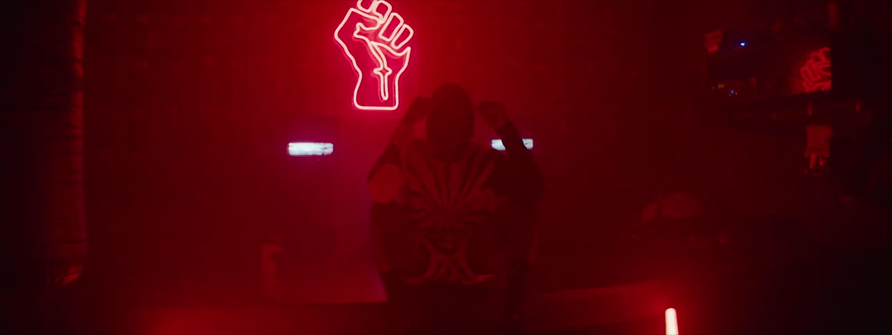 A man sits in a nightclub with brightly flashing lights