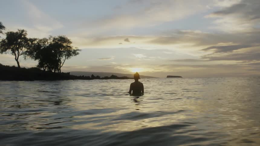 A woman stands in flowing water as the sun shines