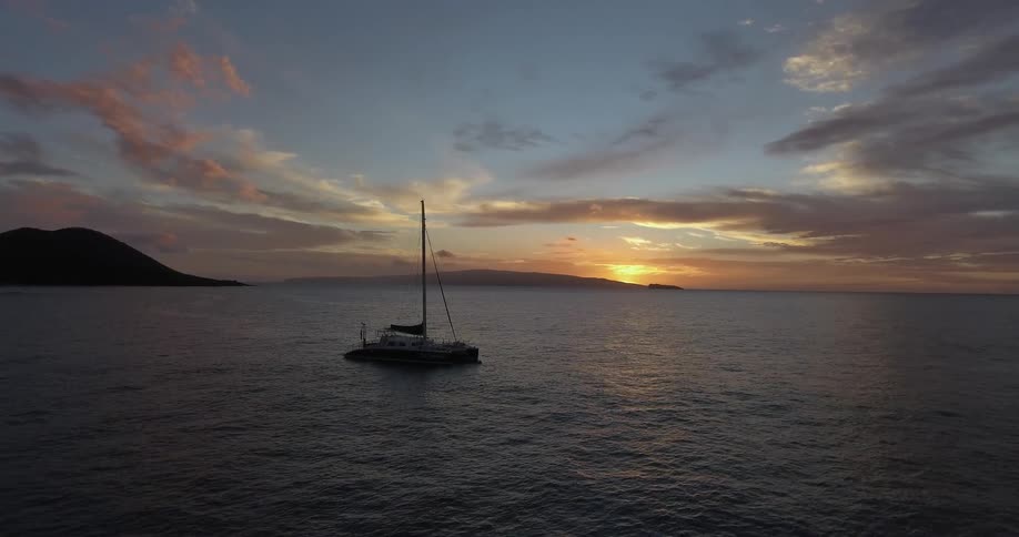 A boat floats anchored in a bay at sunset