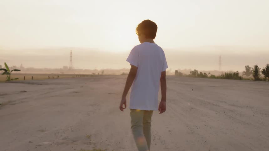 A young man walks outside under the sun