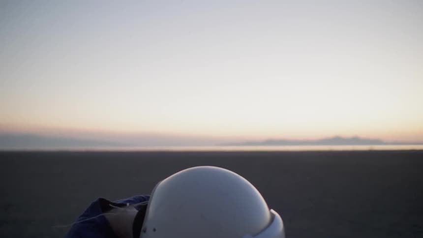 A young boy wears a helmet in a desert at sunset