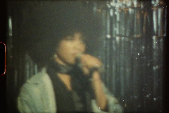 A woman with an afro sings on stage