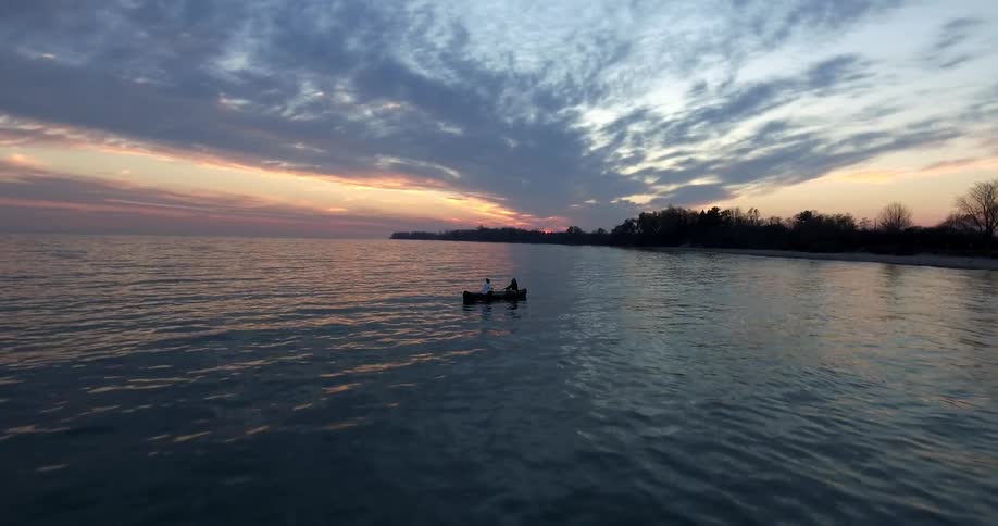 Aerial view of two people  on a canoe at a cloudy sunset