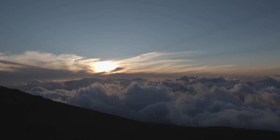 Clouds are seen rolling across the top of a mountain