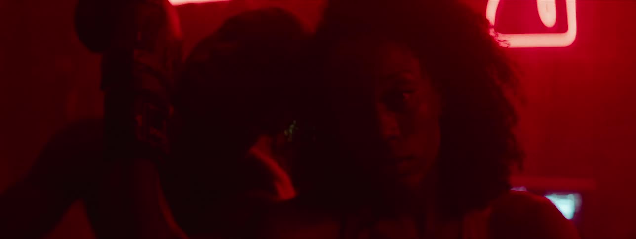 A male and female boxer stand with heads together in a red lit room
