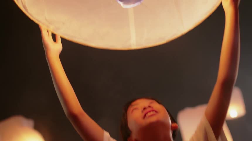 A child raises a paper torch in the sky