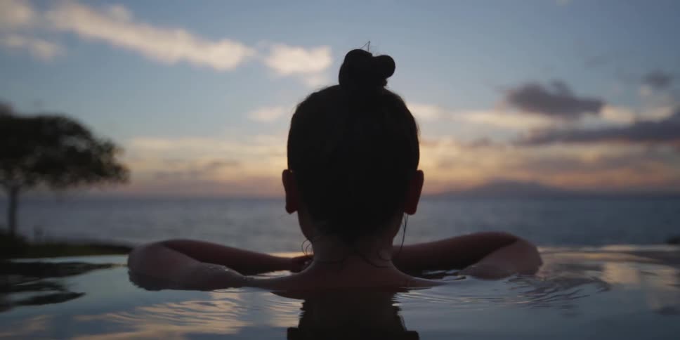 Woman shoulder high in water watching the sun set