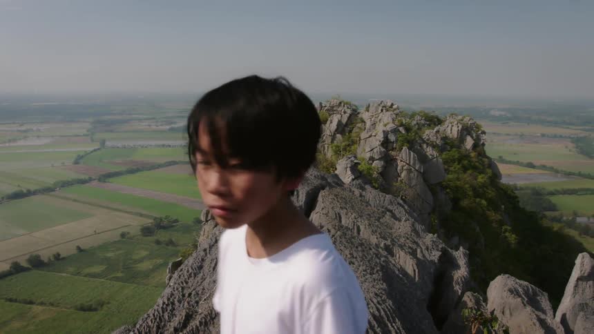 A child is standing on the top of the mountain looking around