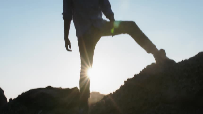 A hiker stands in mountains on a sunny day
