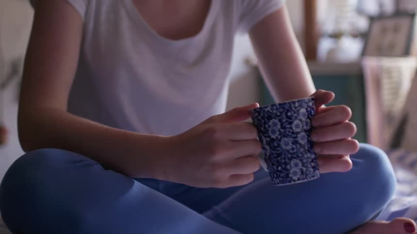 A woman holds a mug tapping it