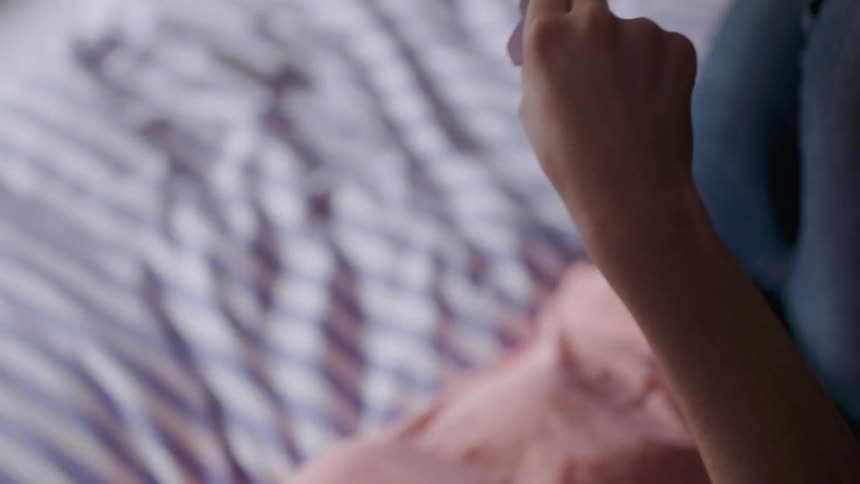 A woman plays with a paper airplane in bed