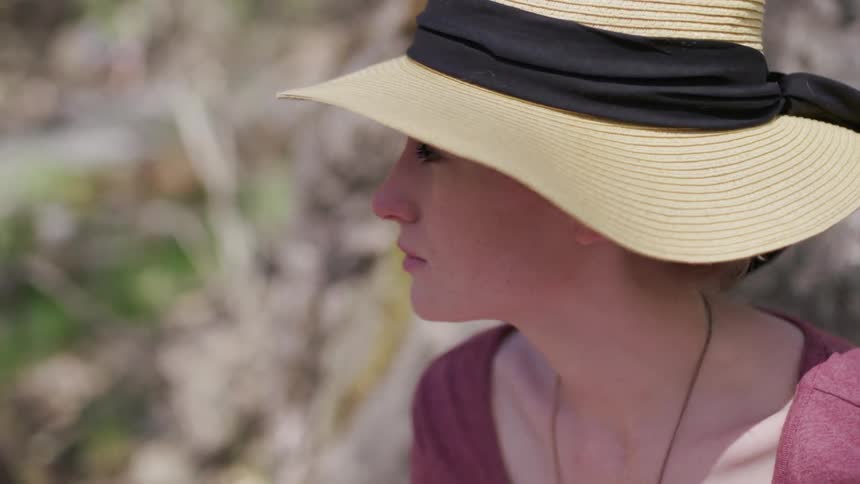 Woman wearing hat is sitting outside and looking around