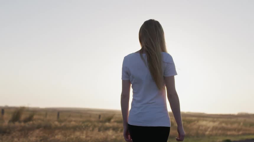 A woman walks next to a grass field