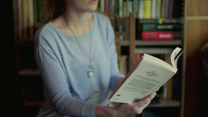 Woman is reading book in library
